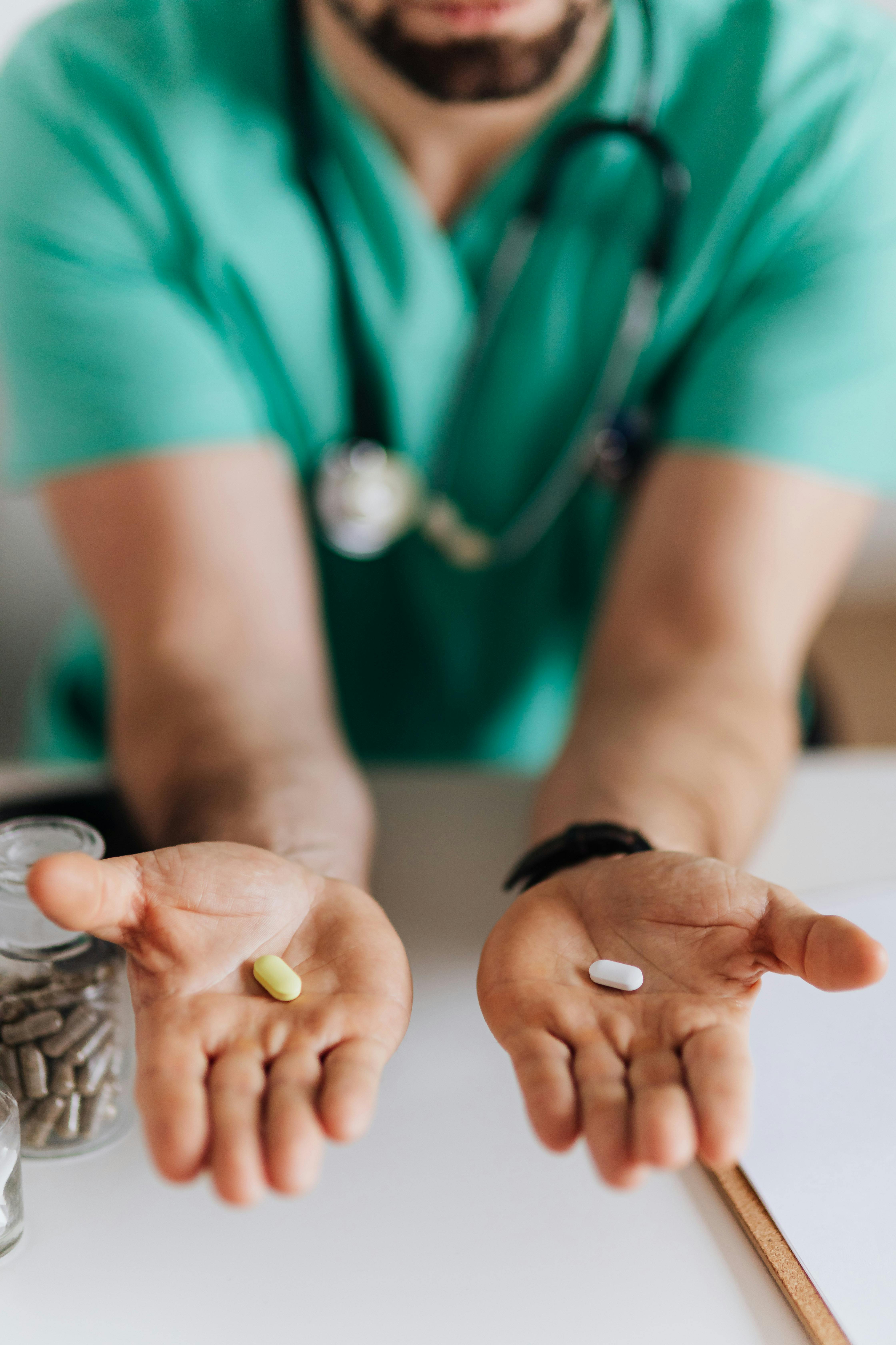 A pill in each outstretched hand of a male doctor